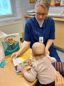 Terveydenhoitaja Aino Hietikko esittelee neuvolassa kirjaa vauvalle.
